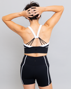 Person wearing a black and white sports bra and shorts on a gray background