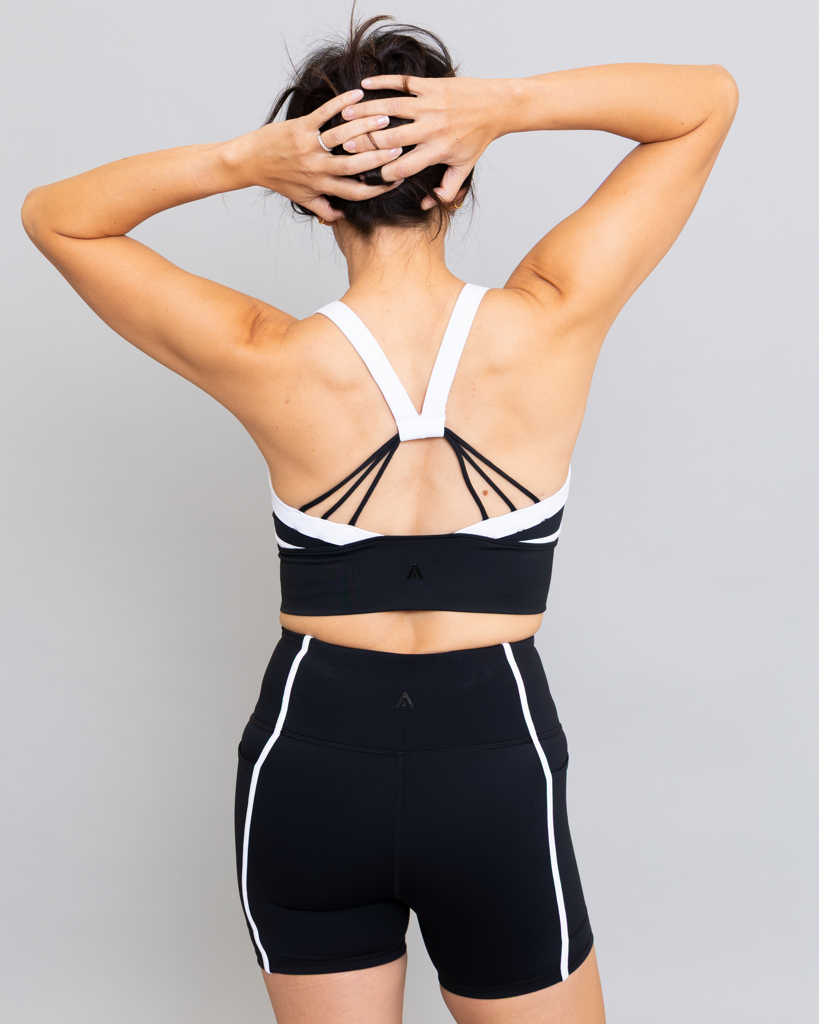 Person wearing a black and white sports bra and shorts on a gray background