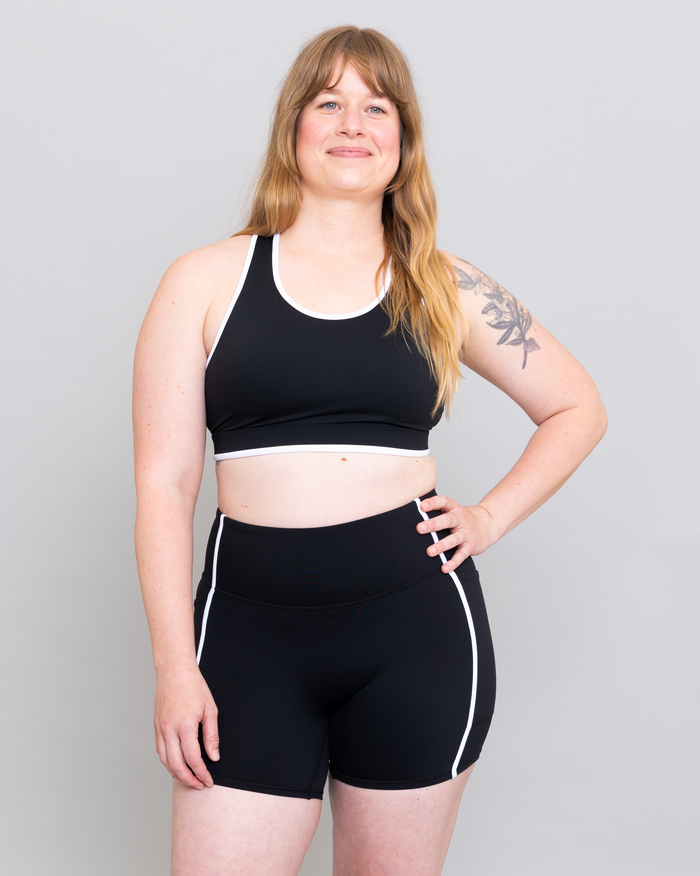 Woman wearing a black sports bra and shorts set on a plain background