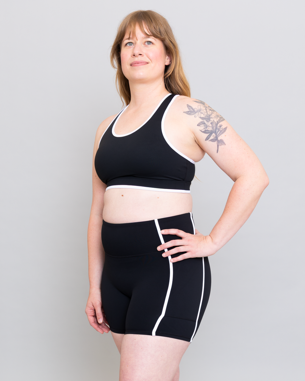 Woman wearing a black sports bra and shorts set on a plain background