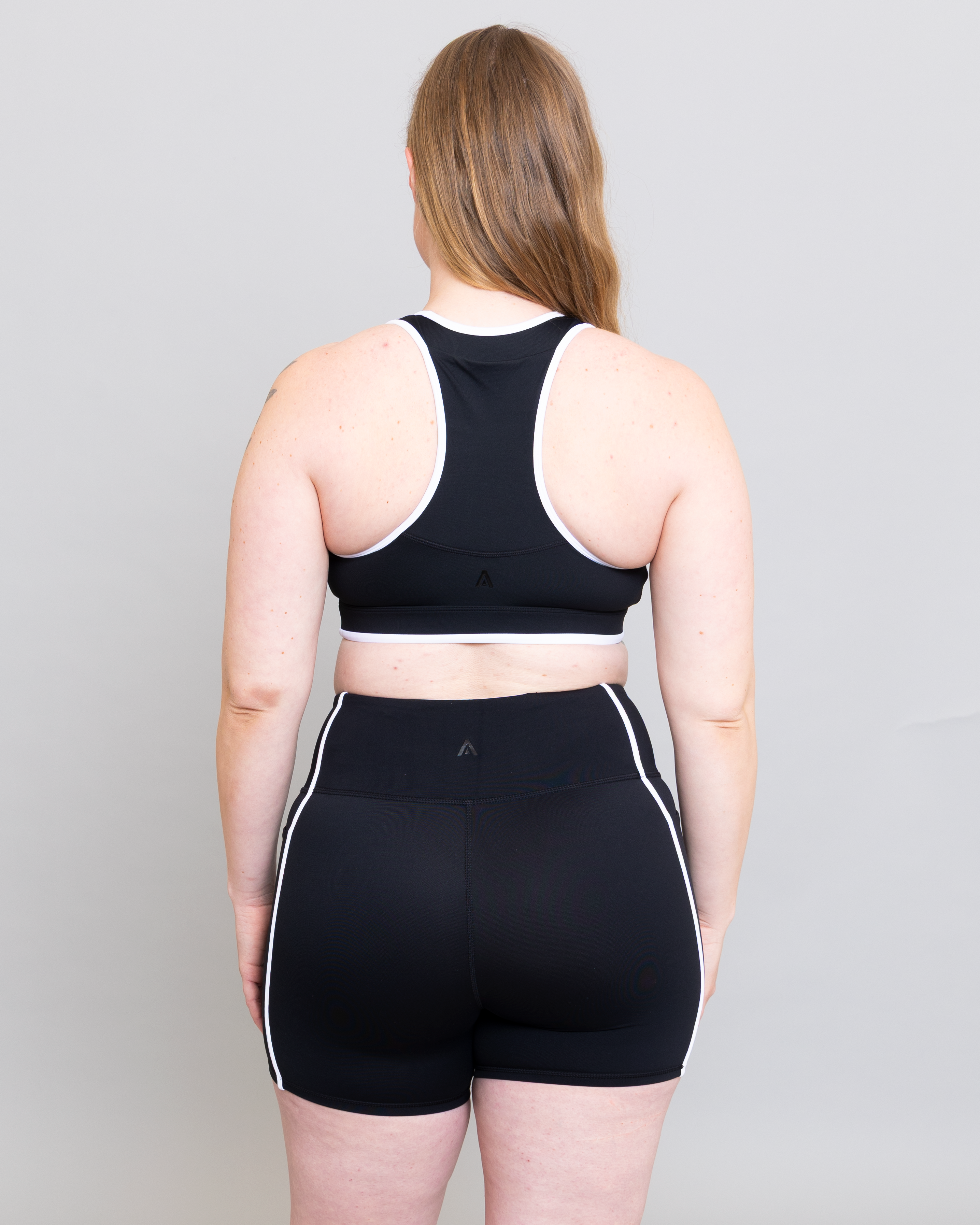 Person wearing a black sports bra and shorts set on a plain background