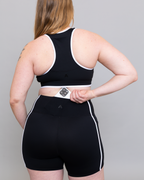 Person wearing a black athletic outfit with white accents on a plain background