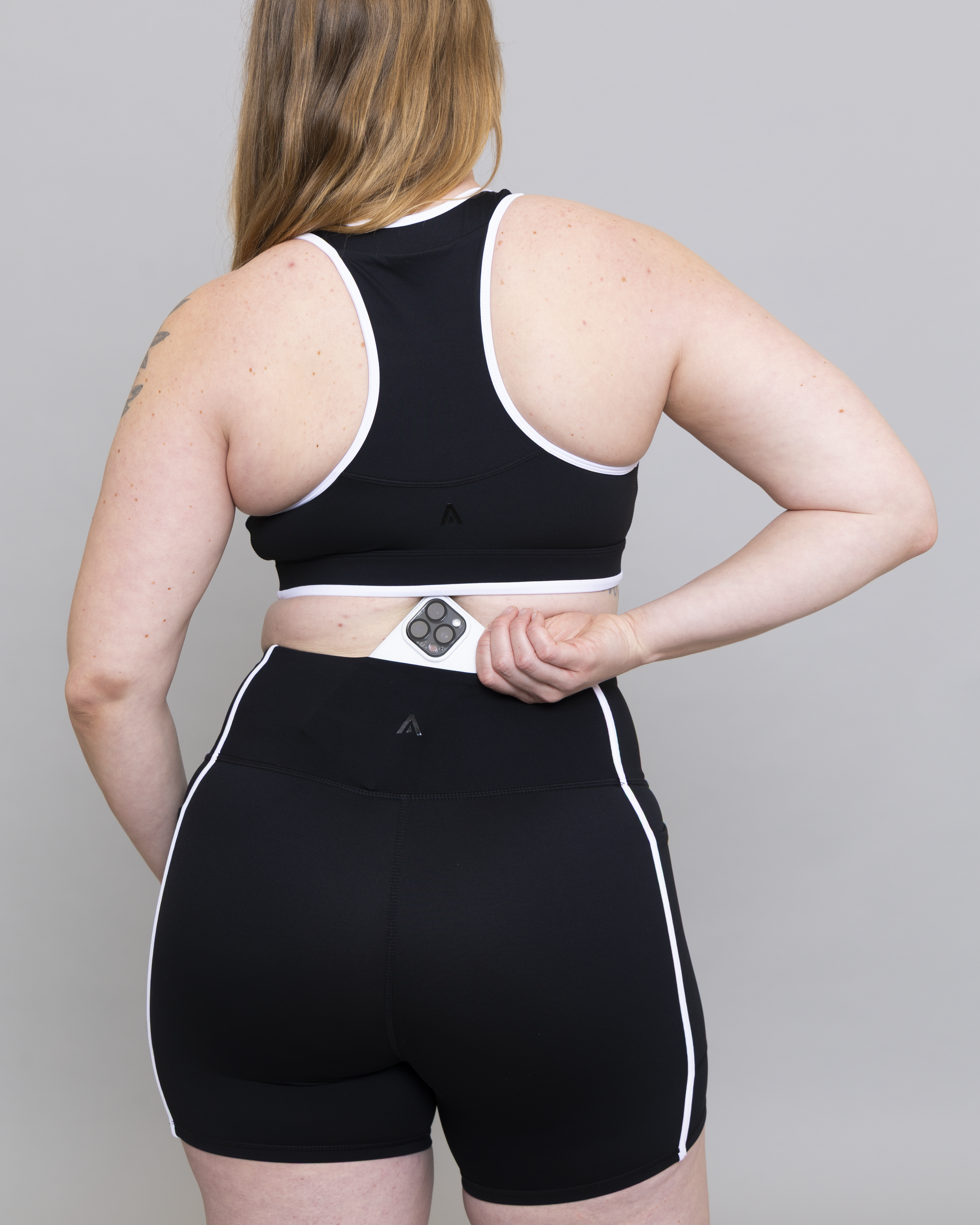 Person wearing a black athletic outfit with white accents on a plain background