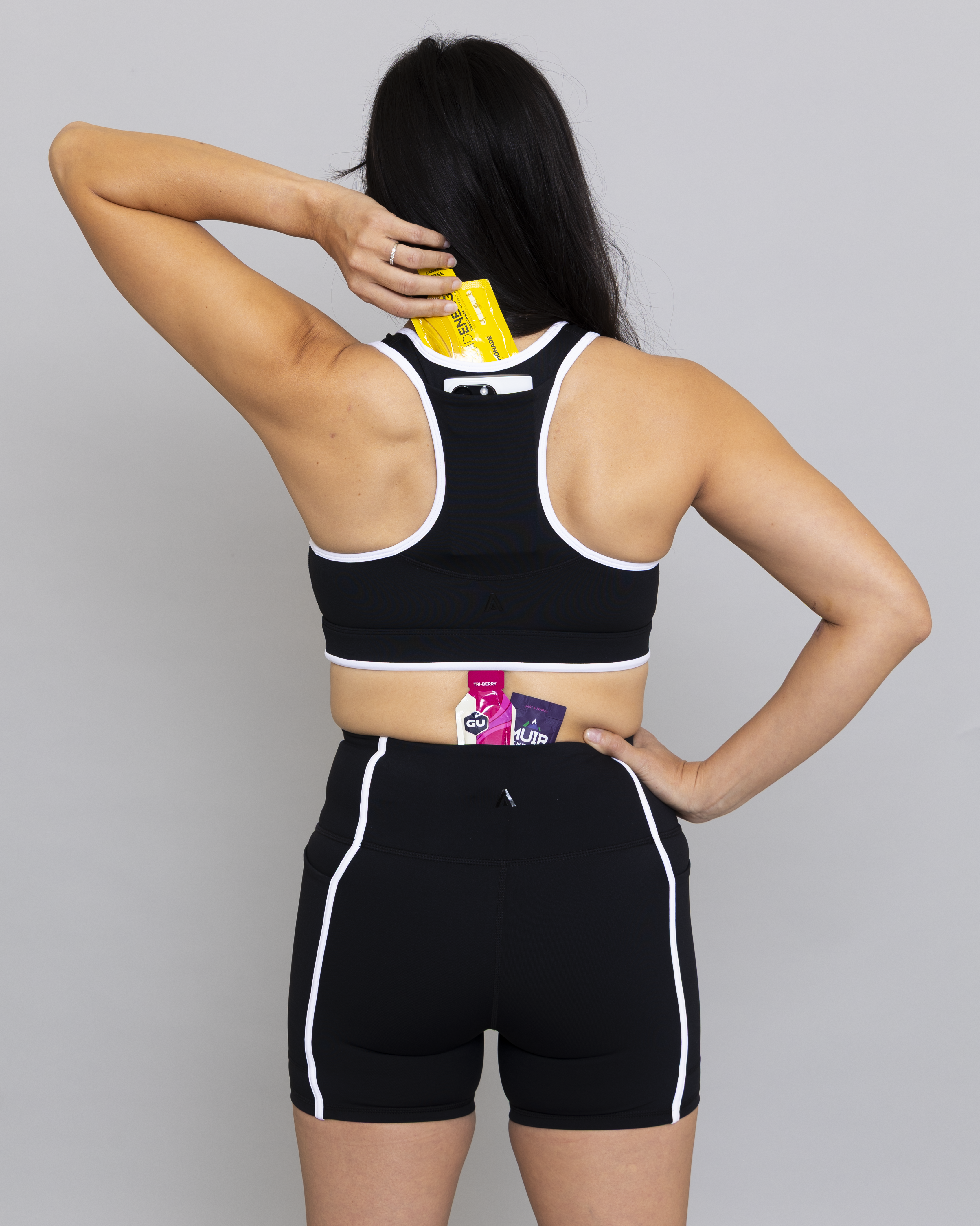 Person wearing a black sports bra and shorts set with visible branding on a gray background