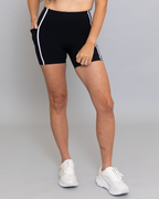 Person wearing black shorts with white stripes on a gray background