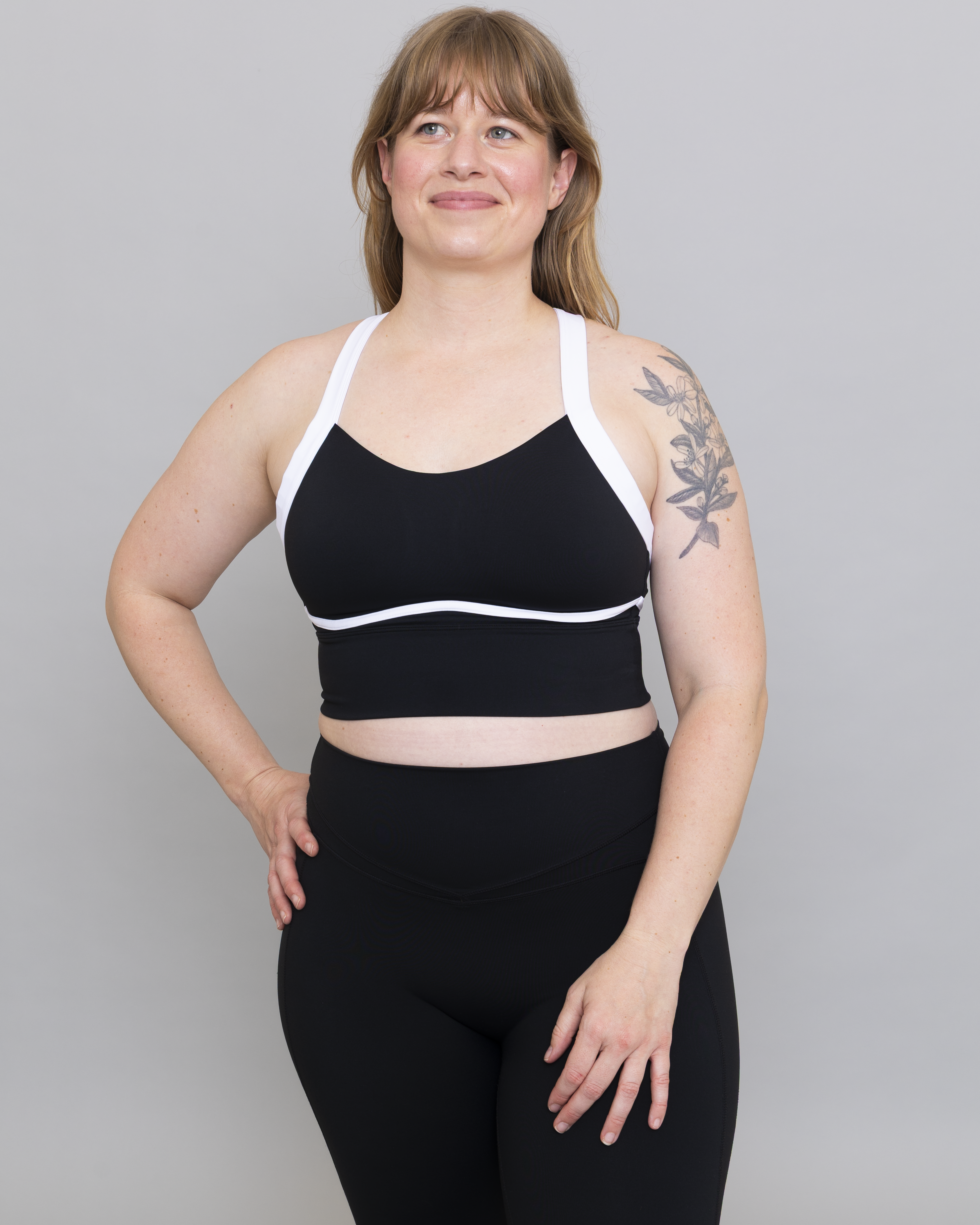 Woman wearing a black sports bra and leggings on a gray background