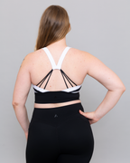 Person wearing a black and white sports bra and leggings on a gray background