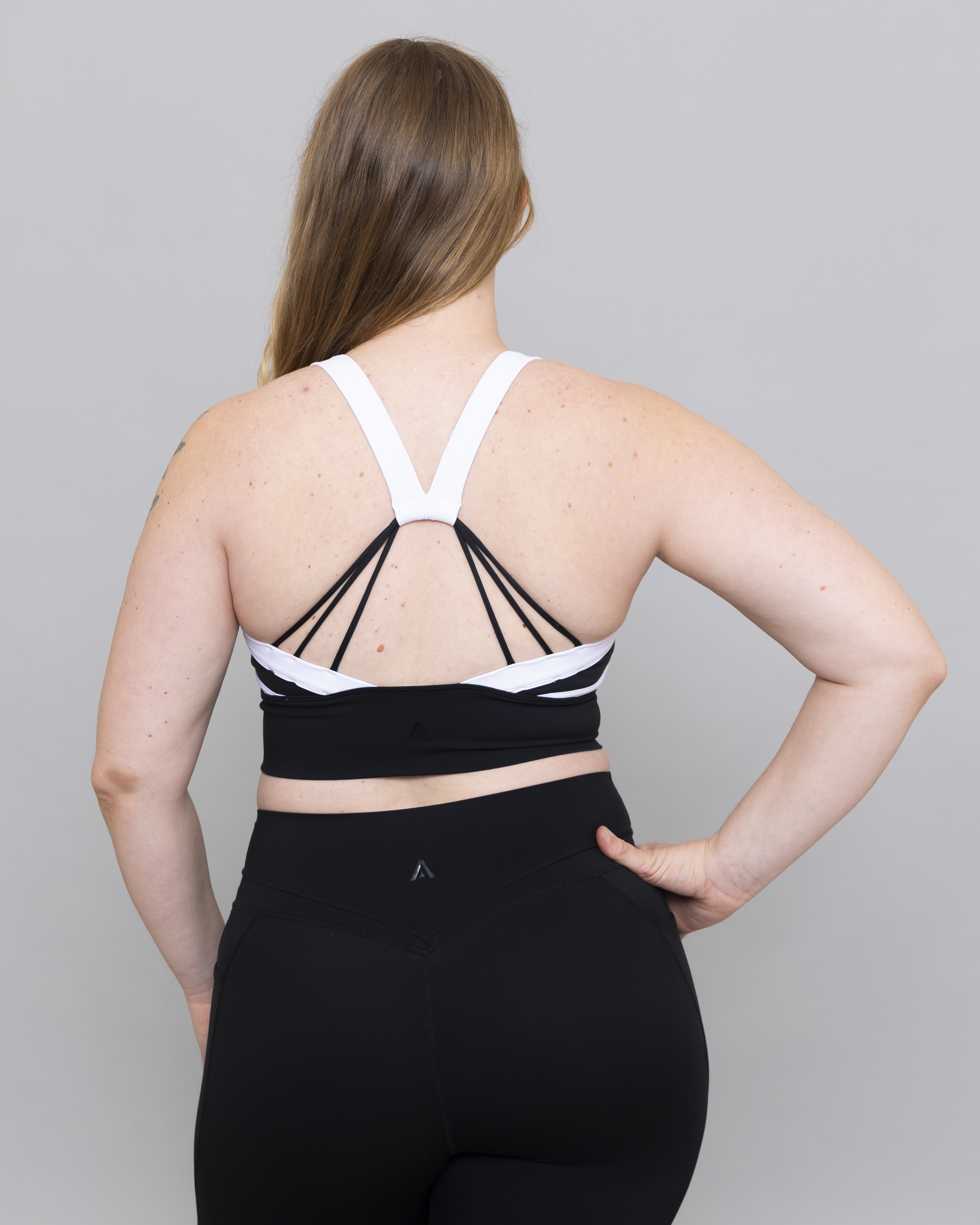 Person wearing a black and white sports bra and leggings on a gray background