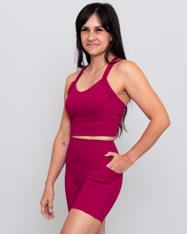 Woman wearing a magenta athletic outfit on a plain background