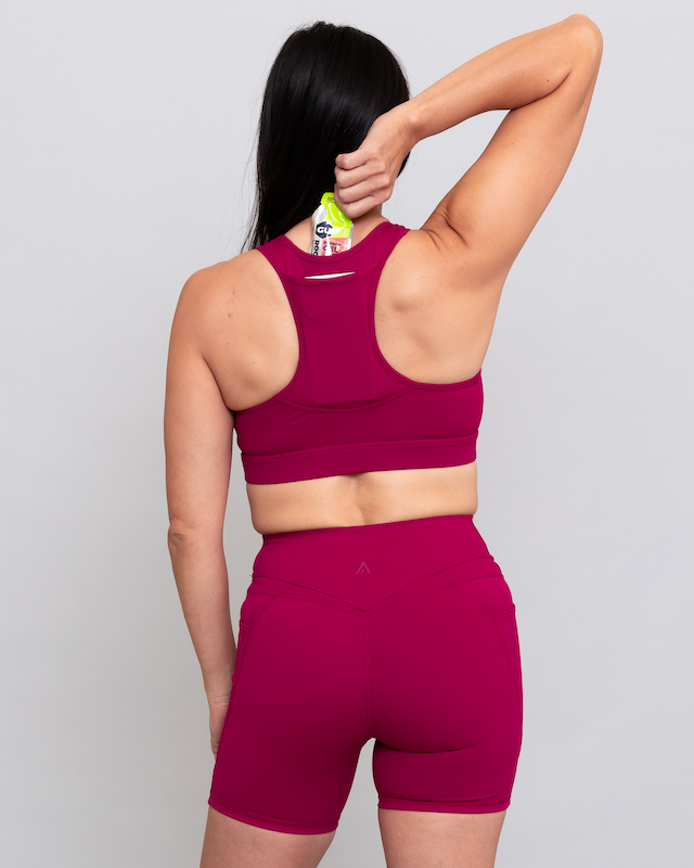 Person wearing a magenta sports bra and shorts set on a light gray background