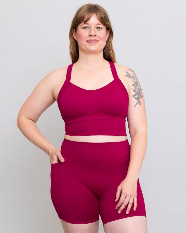 Woman wearing a magenta athletic outfit on a plain background