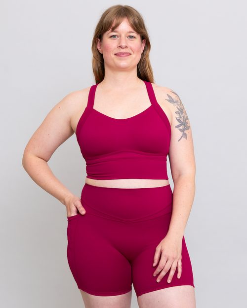 Woman wearing a magenta athletic outfit on a plain background