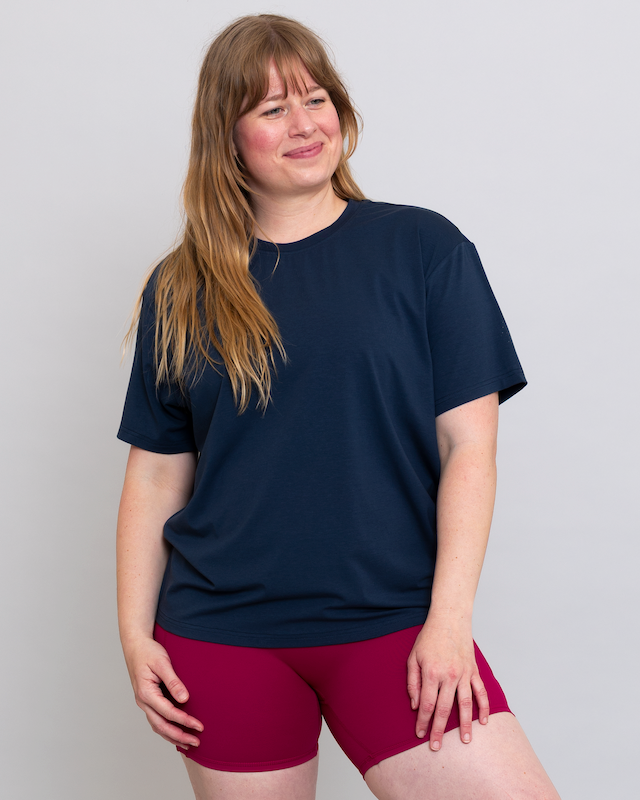 Person wearing a navy blue t-shirt and maroon shorts on a plain background