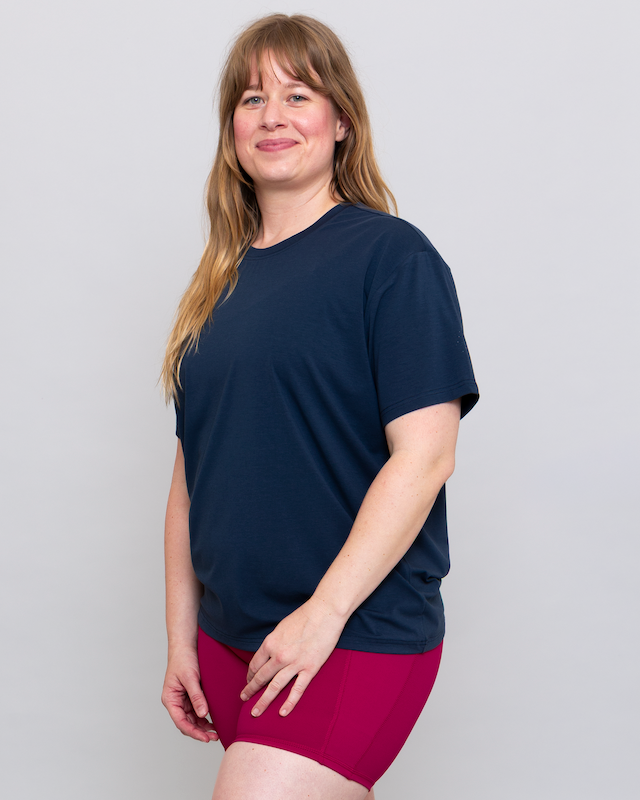 Woman wearing a navy blue t-shirt and maroon shorts on a plain background
