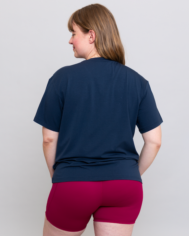 Person wearing a navy blue t-shirt and red shorts on a plain background