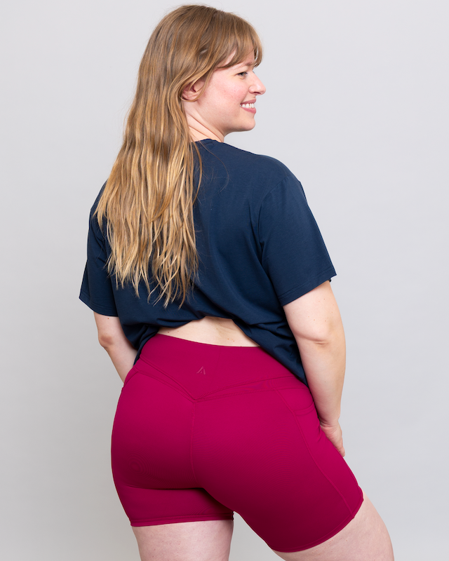 Person wearing a navy blue t-shirt and red shorts on a plain background
