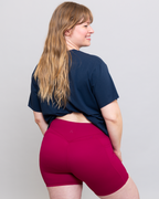Person wearing a navy blue t-shirt and red shorts on a plain background