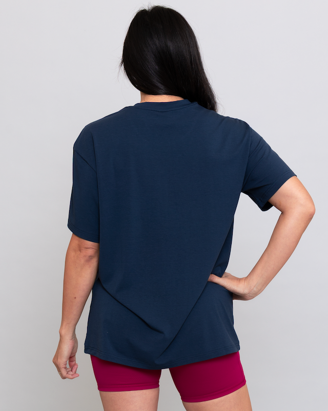 Person wearing a navy blue top and pink shorts on a light gray background