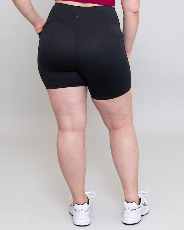 Person wearing black shorts on a plain background
