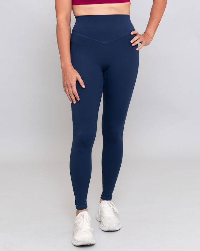 Person wearing navy leggings on a gray background