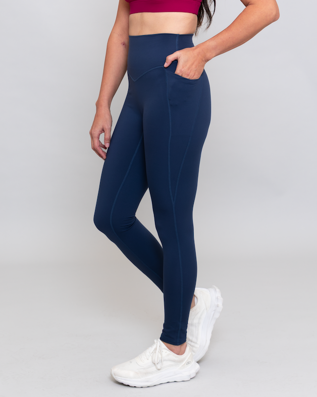 Person wearing navy leggings and white sneakers on a light gray background