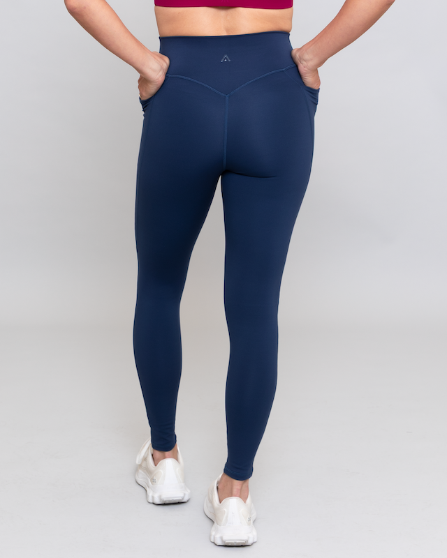 Person wearing navy leggings on a gray background