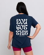 Person wearing a navy blue t-shirt with 'YOU GOT THIS' text on the back, standing against a plain background.